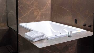 Un baño moderno con una bañera grande, un espejo y paredes de mármol.