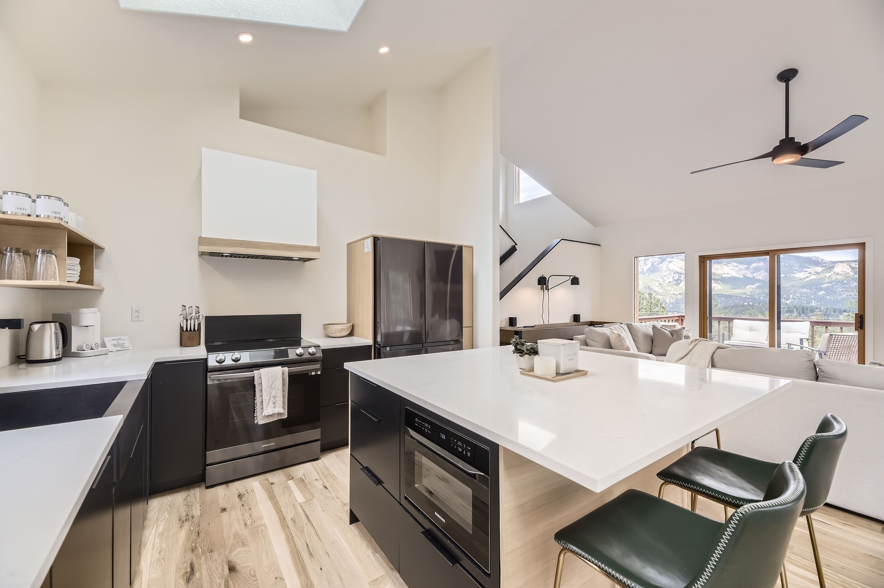 Una cocina moderna con una isla central, electrodomésticos integrados y vistas a un balcón.
