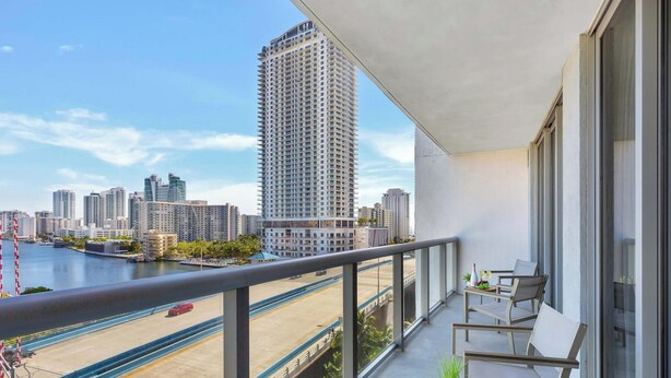 Uma varanda com vista para o horizonte urbano, incluindo edifícios altos e um corpo de água.