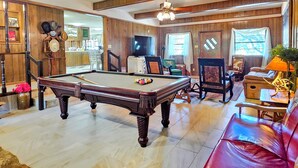A pool table in a room with wooden paneling, a television, and a red leather sofa. - Enjoy Longhorns at Texas Ranch House near Canyon Lake & Gruene – Sleeps 12 (New Braunfels)