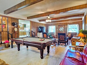 A pool table in a room with wooden paneling, a television, and a red leather sofa. - Enjoy Longhorns at Texas Ranch House near Canyon Lake & Gruene – Sleeps 12 (New Braunfels)