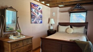 A bedroom with a wooden bed, a dresser, a mirror, and a painting on the wall.