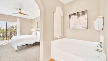A bedroom with a bed, a ceiling fan, a large window, and a balcony.