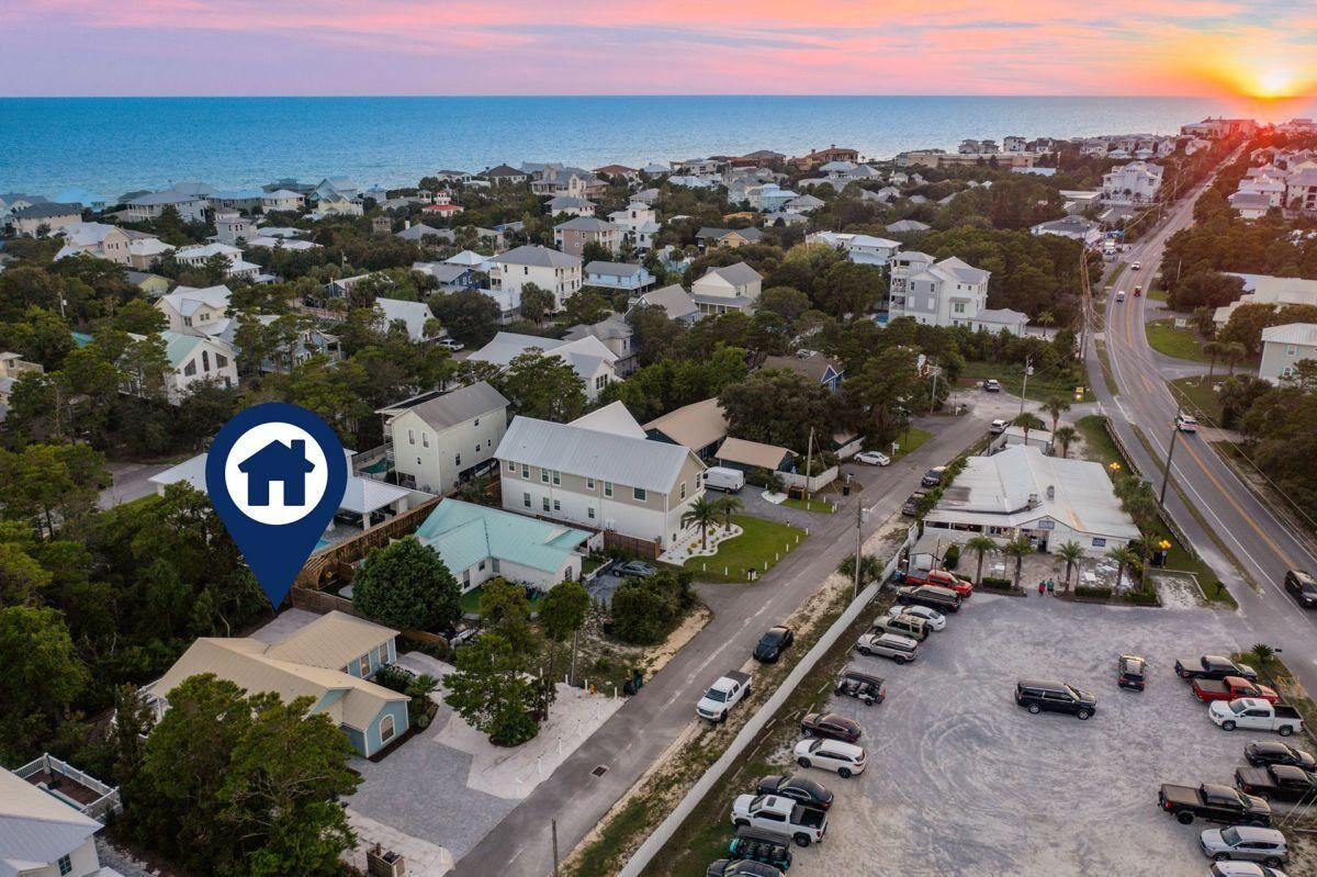 A residential area with houses, a parking lot, and a road leading to the sea.