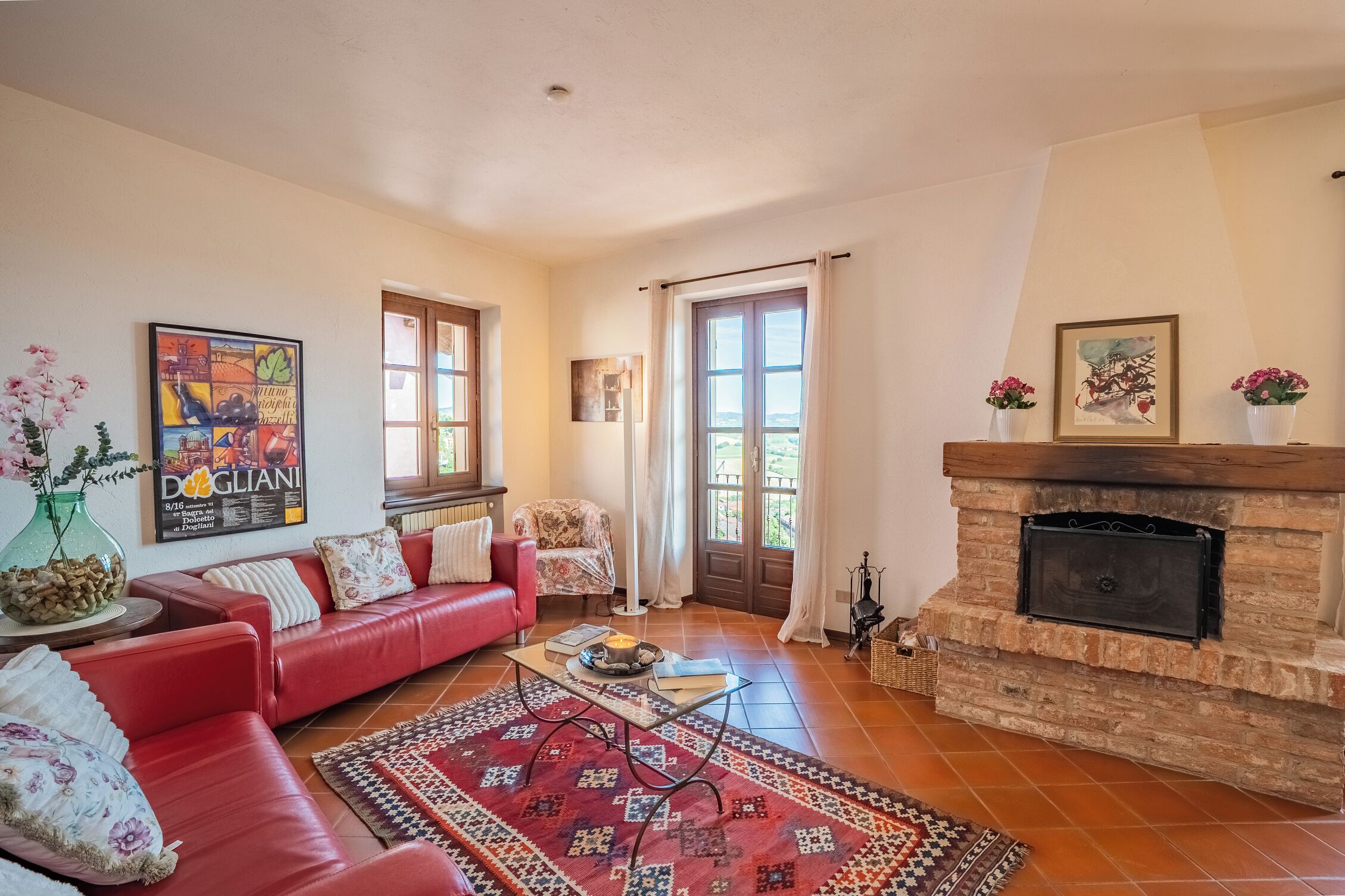 A cozy living room with a red sofa, a fireplace, and a large window.