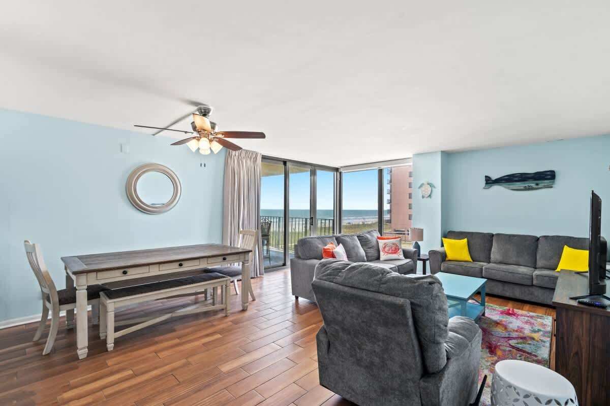 A living room with a dining table, sofa, and a ceiling fan.