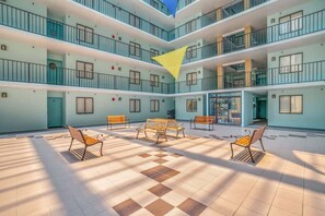 Ein mehrgeschossiges Atrium mit Schachbrettmuster-Boden, Bänken und einer dreieckigen, hängenden Dekoration.