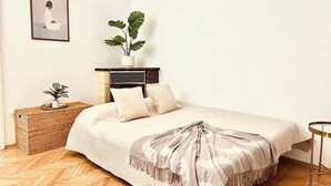 A neatly arranged bedroom with a bed, bedside table, and a potted plant. - Servus Homes - rooftop terrace & balcony - Metro (Vienna)