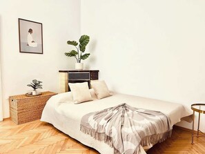 Ein ordentlich eingerichtetes Schlafzimmer mit Bett, Nachttisch und einer Topfpflanze.
