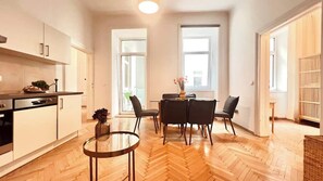 A modern kitchen with a dining area, wooden flooring, and large windows. - Servus Homes - rooftop terrace & balcony - Metro (Vienna)