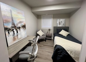 A bedroom with a bed, a desk, a chair, a nightstand, and a window. - Modern 2BR Retreat | Fully Equipped | 31+ Day Stays — minutes to downtown Ottawa (Ottawa)