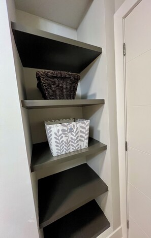 A set of shelves with baskets and storage boxes. - Modern 2BR Retreat | Fully Equipped | 31+ Day Stays — minutes to downtown Ottawa (Ottawa)