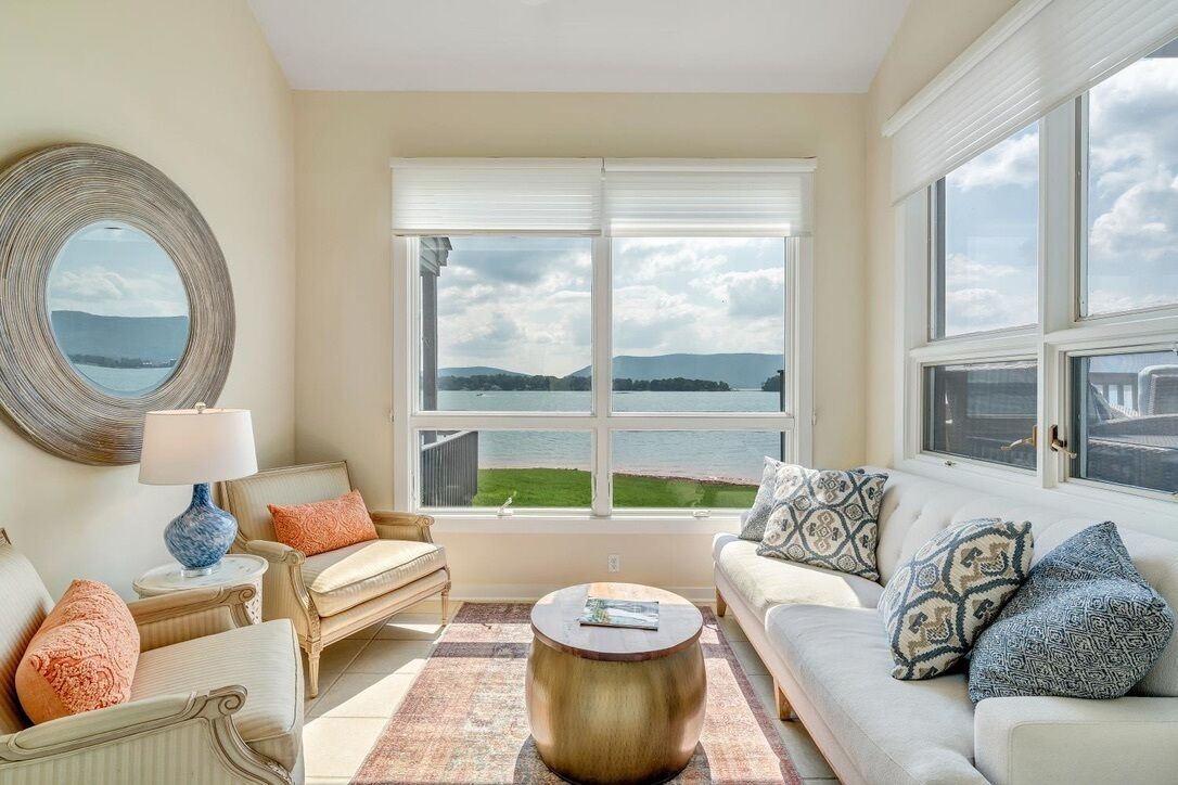 Un salon avec vue sur un lac et des montagnes, aménagé avec un canapé, des fauteuils et une table basse.