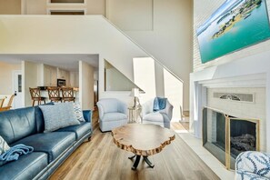 Uma sala de estar moderna com um sofá azul, uma mesa de centro redonda e uma lareira.