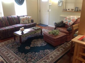 A living room with a sofa, a coffee table, a brown leather chair, and a patterned rug.