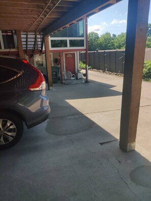 A covered parking area with a car parked under a wooden structure.