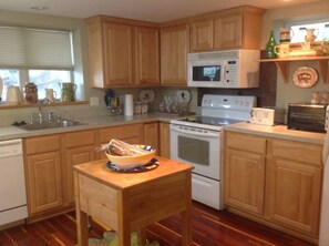 A kitchen with wooden cabinets, a microwave, an oven, and a sink.