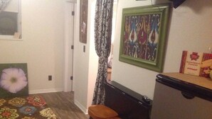 A compact kitchen with a refrigerator, a microwave, and a small table with two stools. - Downtown Bohemian Bungalow Full Bed Bottom TwinTop (Fayetteville)