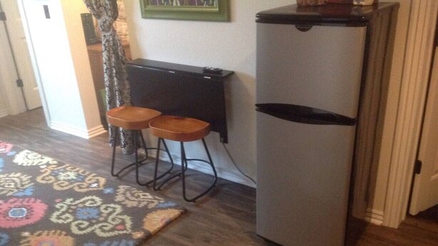 A kitchen with a refrigerator, two stools, and a patterned rug. - Downtown Bohemian Bungalow Full Bed Bottom TwinTop (Fayetteville)