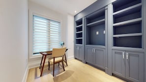 Una habitación con escritorio, silla y estanterías empotradas.