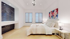 A bedroom with a bed, bedside table, lamp, artwork, and a large window with blinds. - Executive Home in Toronto [4 bedrooms\4 Bath] (Toronto)