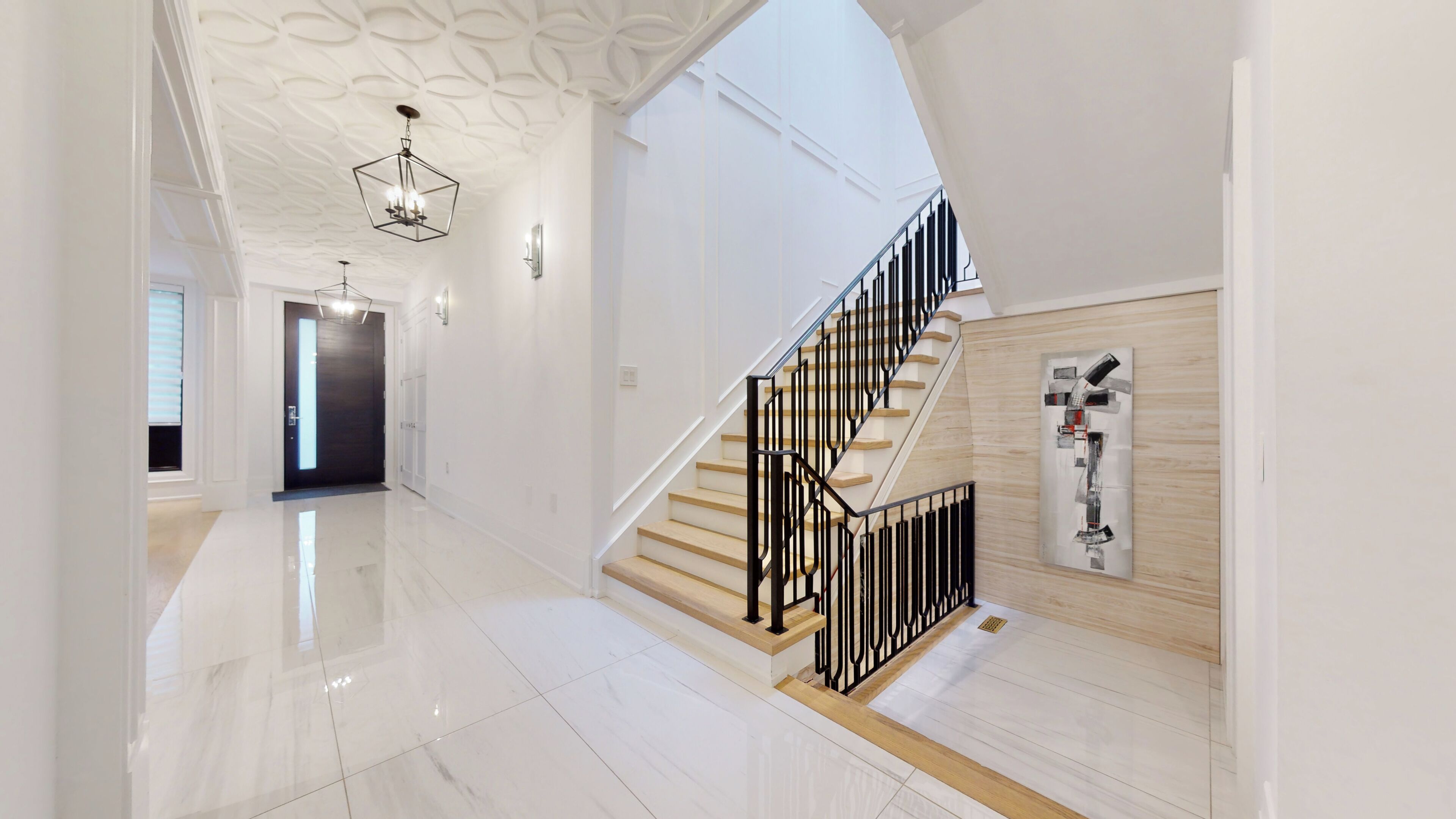 A modern interior with a polished marble floor, a staircase with black railings, and a geometric ceiling design.