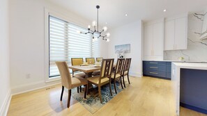 A modern kitchen with white cabinets, a marble backsplash, and a dining area with a wooden table and chairs. - Executive Home in Toronto [4 bedrooms\4 Bath] (Toronto)
