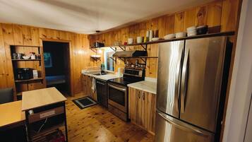 A compact kitchen with wooden cabinets, a stainless steel refrigerator, a sink, and a countertop with various kitchen items.