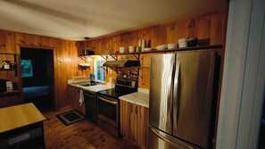 A kitchen with wooden paneling, stainless steel appliances, and a countertop with various items.