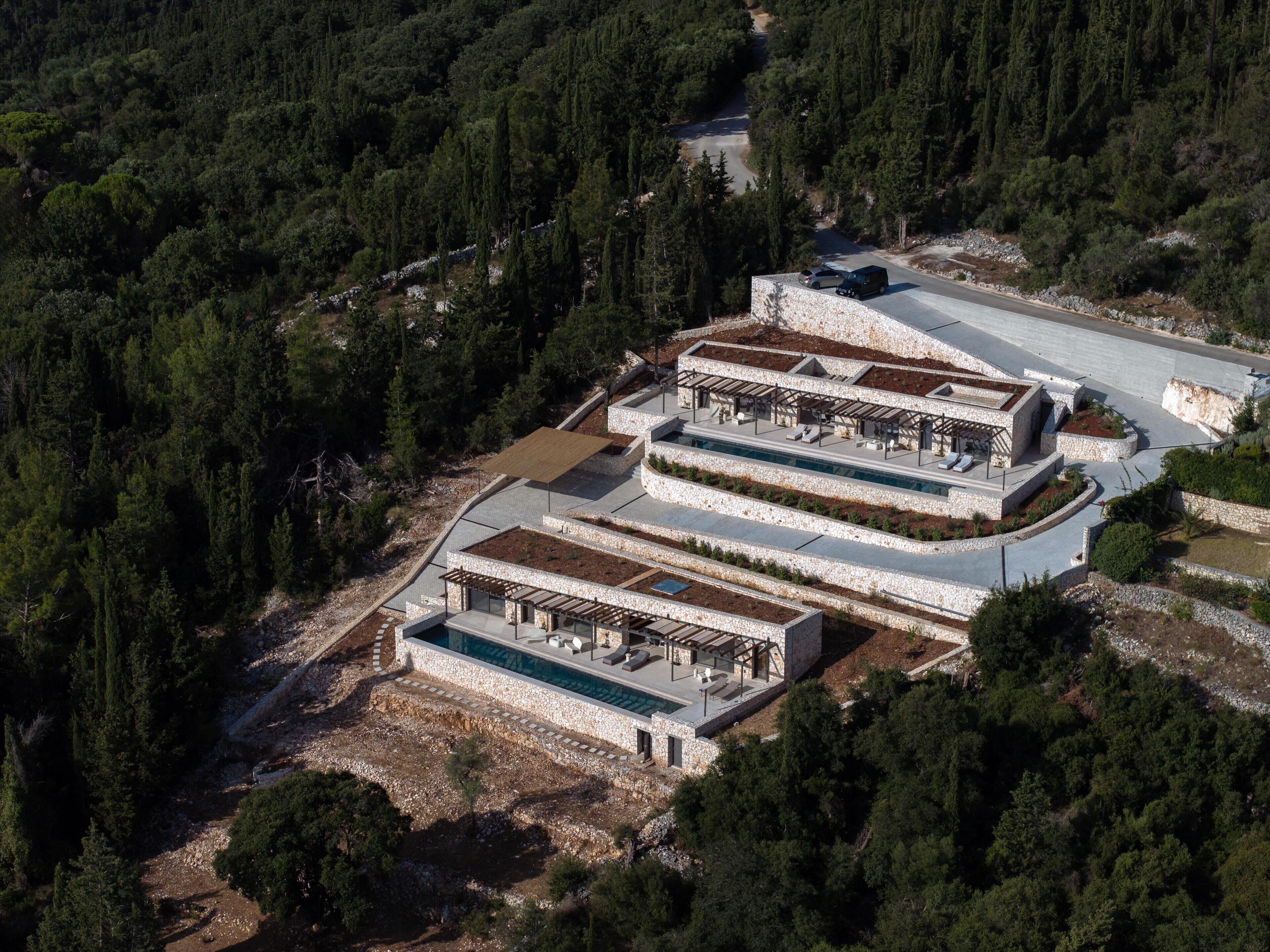A multi-level building with outdoor terraces and a swimming pool, surrounded by dense forest.
