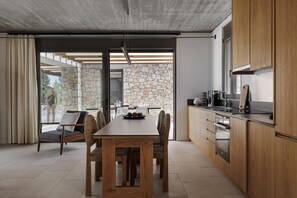 Eine moderne Küche mit Holzschränken, einem Esstisch mit Stühlen und einer Steinwand.