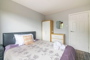 Ein Schlafzimmer mit Bett, Kleiderschrank, Spiegel und Tür.