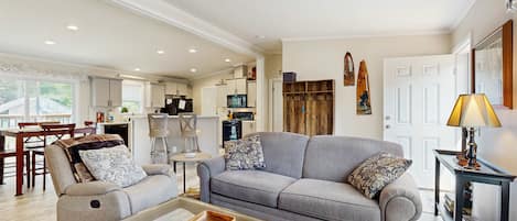 Ein modernes Wohnzimmer mit grauem Sofa, einem Couchtisch und einem Essbereich mit Holztisch und Stühlen.