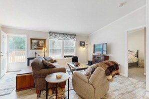 Un salon comprenant un canapé, un fauteuil, une table basse et un téléviseur.