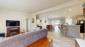 Uma sala de estar ampla, com televisão de tela plana, um sofá e um banco de madeira.