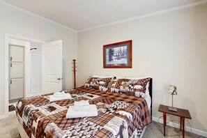 A bedroom with a bed, a door, a framed picture on the wall, and a small table with a lamp. - Blackhawk Retreat- Near Lakes, Trails & Golf (Arkdale)