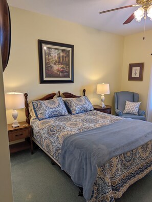 A bedroom with a large bed, two bedside tables with lamps, a chair, a ceiling fan, and a framed picture on the wall. - 2BR, 1 1/2Ba, Kitch, TV rm, laundry rm, 2 patios w full views the Tellico Lake. (Loudon)