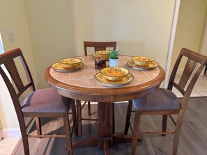 A round wooden dining table with six chairs, a potted plant, and decorative bowls. - 2BR, 1 1/2Ba, Kitch, TV rm, laundry rm, 2 patios w full views the Tellico Lake. (Loudon)