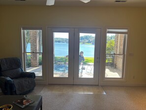 A living room with a large sliding glass door leading to a patio with outdoor furniture and a view of a lake. - 2BR, 1 1/2Ba, Kitch, TV rm, laundry rm, 2 patios w full views the Tellico Lake. (Loudon)