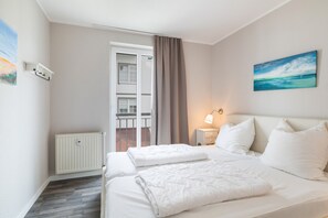 Ein Hotelzimmer mit Bett, Nachttisch, einem Gemälde und Blick nach draußen.