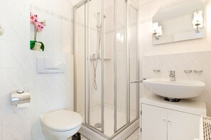 A modern bathroom with a glass-enclosed shower, a white toilet, and a sink with a mirror above it. - Apartment 'Haus Buskam 29 - Räder Erlebnisbad' with Sea View, Balcony and Wi-Fi (Göhren)