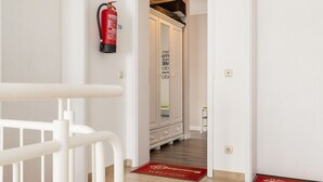 A hallway with a fire extinguisher mounted on the wall, a door with a welcome mat, and a cabinet with drawers. - Apartment 'Haus Buskam 29 - Räder Erlebnisbad' with Sea View, Balcony and Wi-Fi (Göhren)