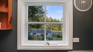 Ein Fenster mit Blick auf ein Haus und Bäume.