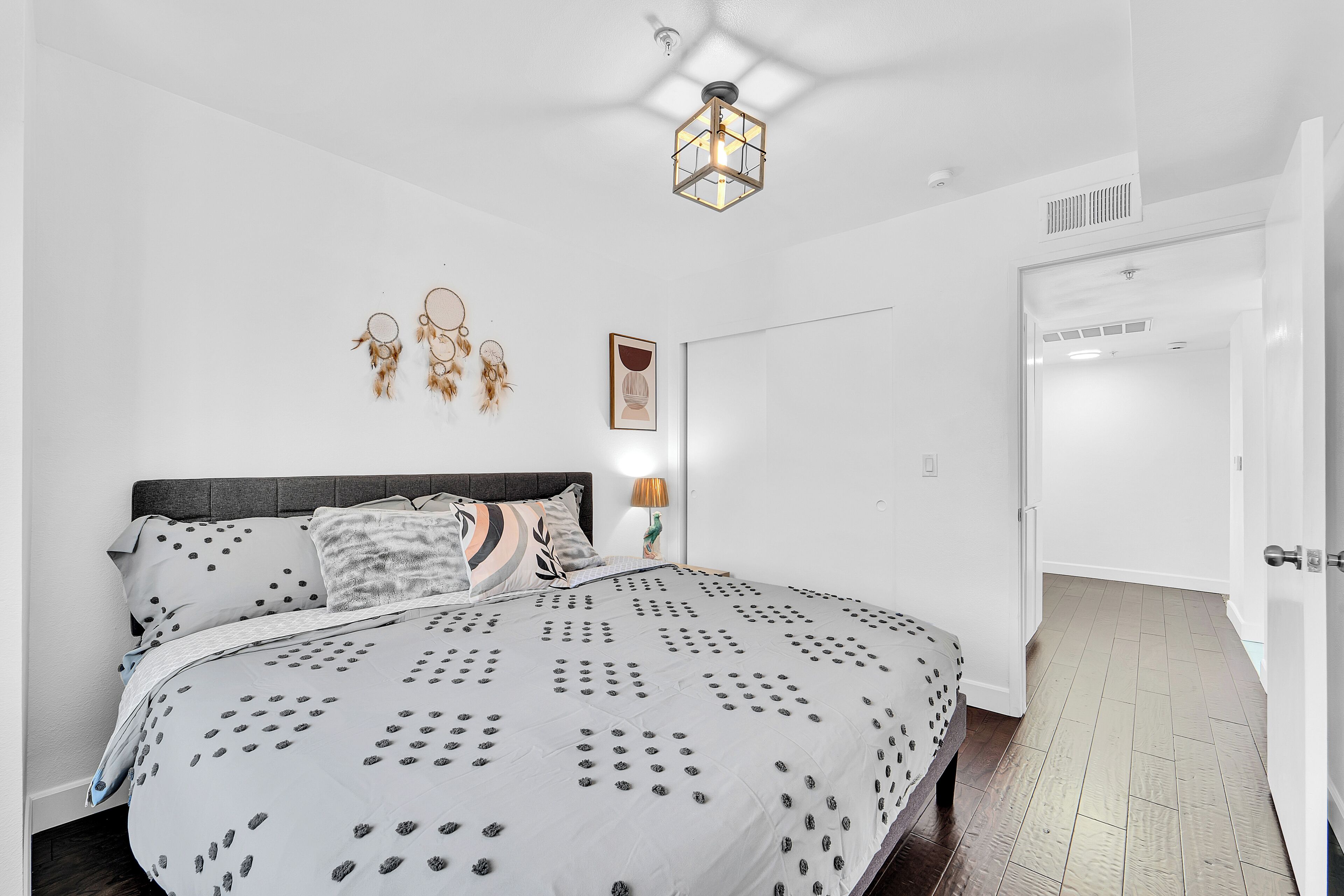 Un dormitorio con una cama grande, una mesita de noche con una lámpara, y un aplique en la pared.