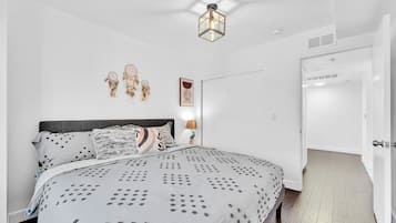 Un dormitorio con una cama grande, una mesita de noche con una lámpara, y un aplique en la pared.