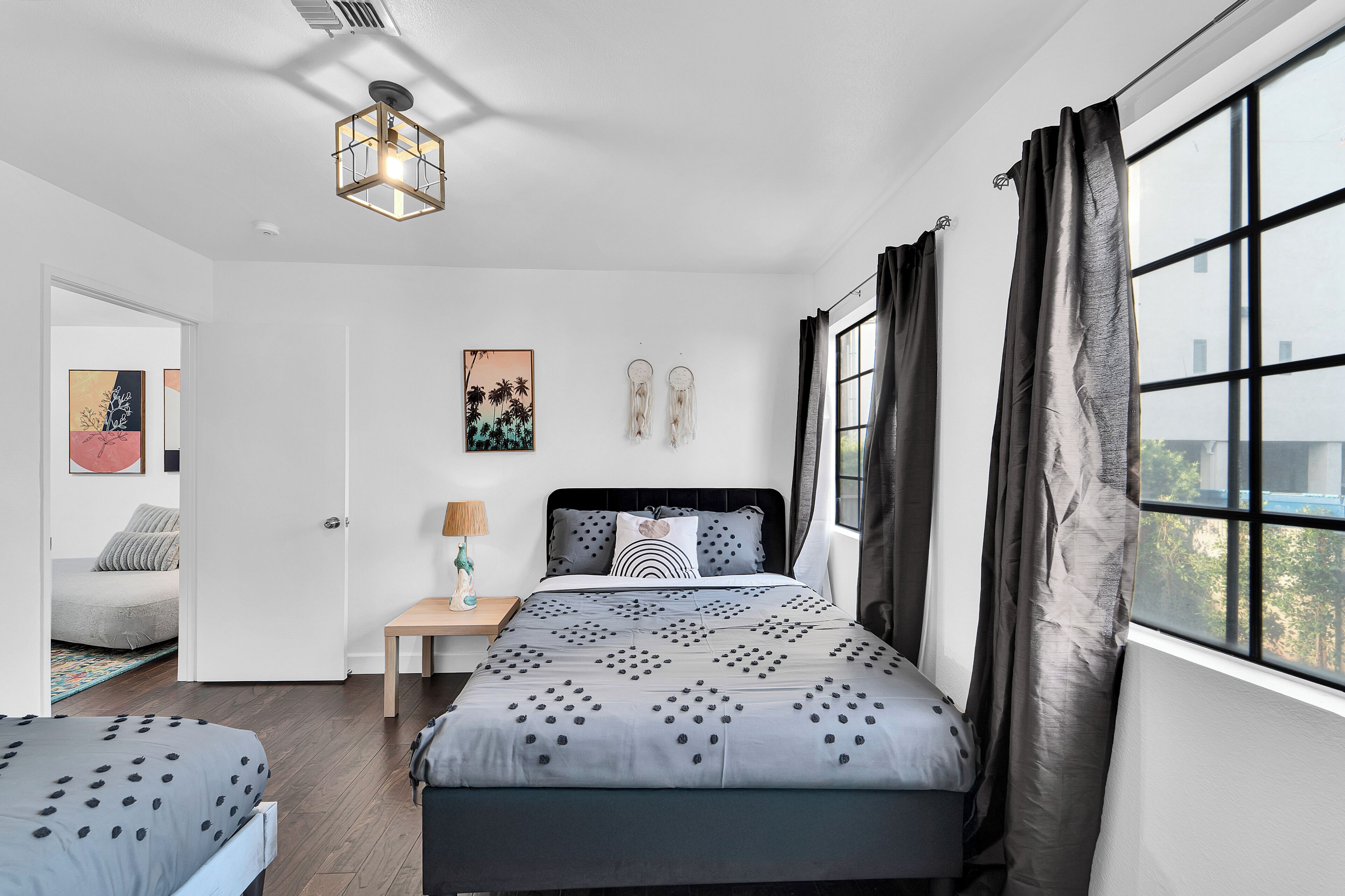 Une chambre à coucher comprenant un lit, une table de chevet, une lampe et une fenêtre donnant sur l’extérieur.
