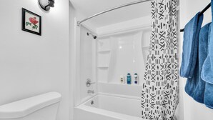 Ein Badezimmer mit einer weißen Badewanne, einer Duschvorhang und einem gerahmten Bild an der Wand.