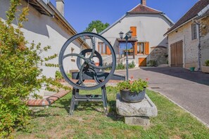 Una vecchia pompa per acqua in un giardino, con una casa sullo sfondo.