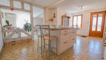 A kitchen with a central island, bar stools, and a wooden floor.