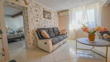 A living room with a sofa, a round table, and a potted plant.